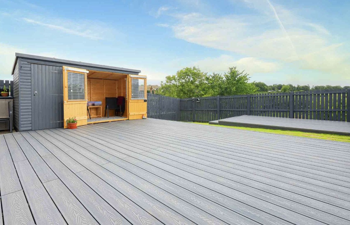 Large gray composite deck with outdoor shed and fenced backyard space
